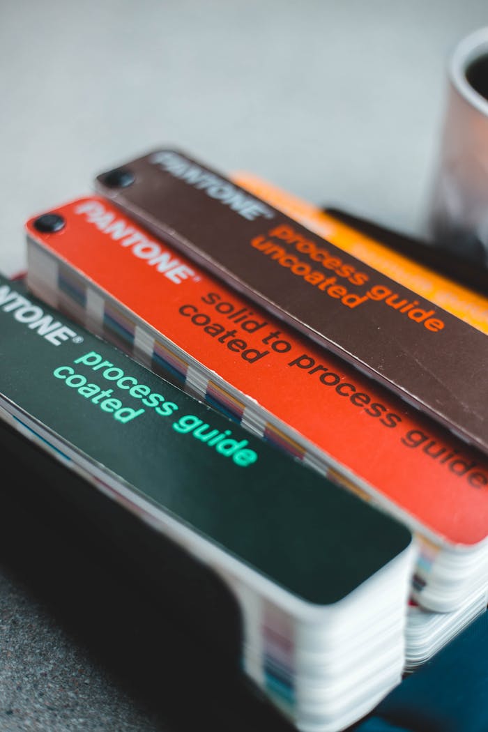 Stack of Pantone color swatches showcasing various coated and uncoated process guides for design work.